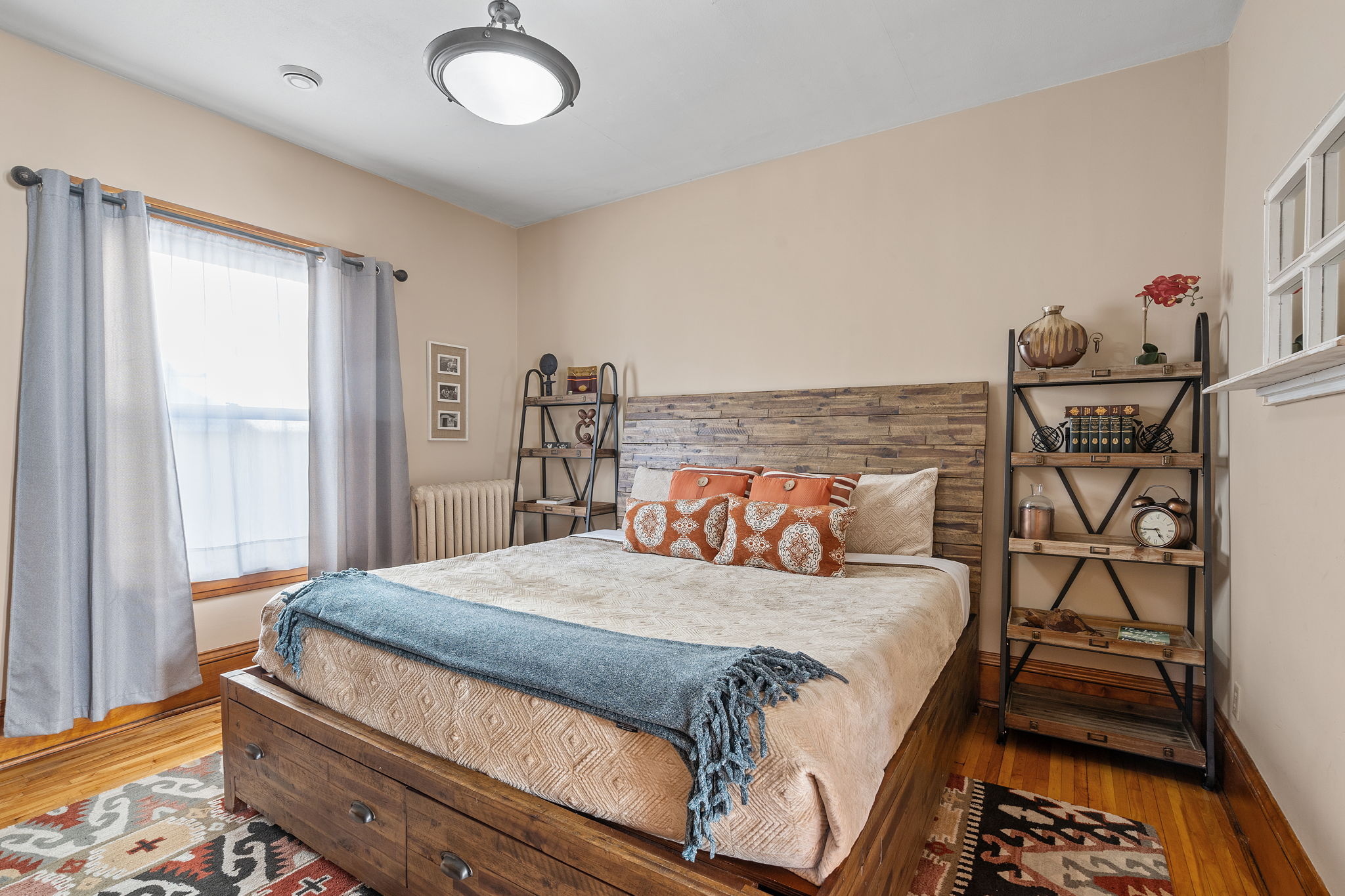 A cozy bedroom featuring a wooden bed, stylish decor, and natural light.