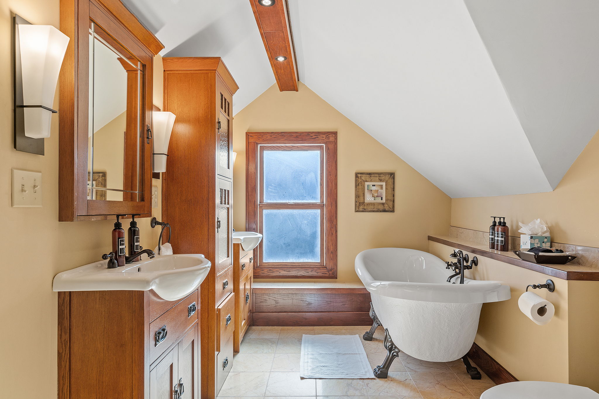 A charming vintage-style bathroom with modern elements, featuring a freestanding bathtub and wooden cabinetry.