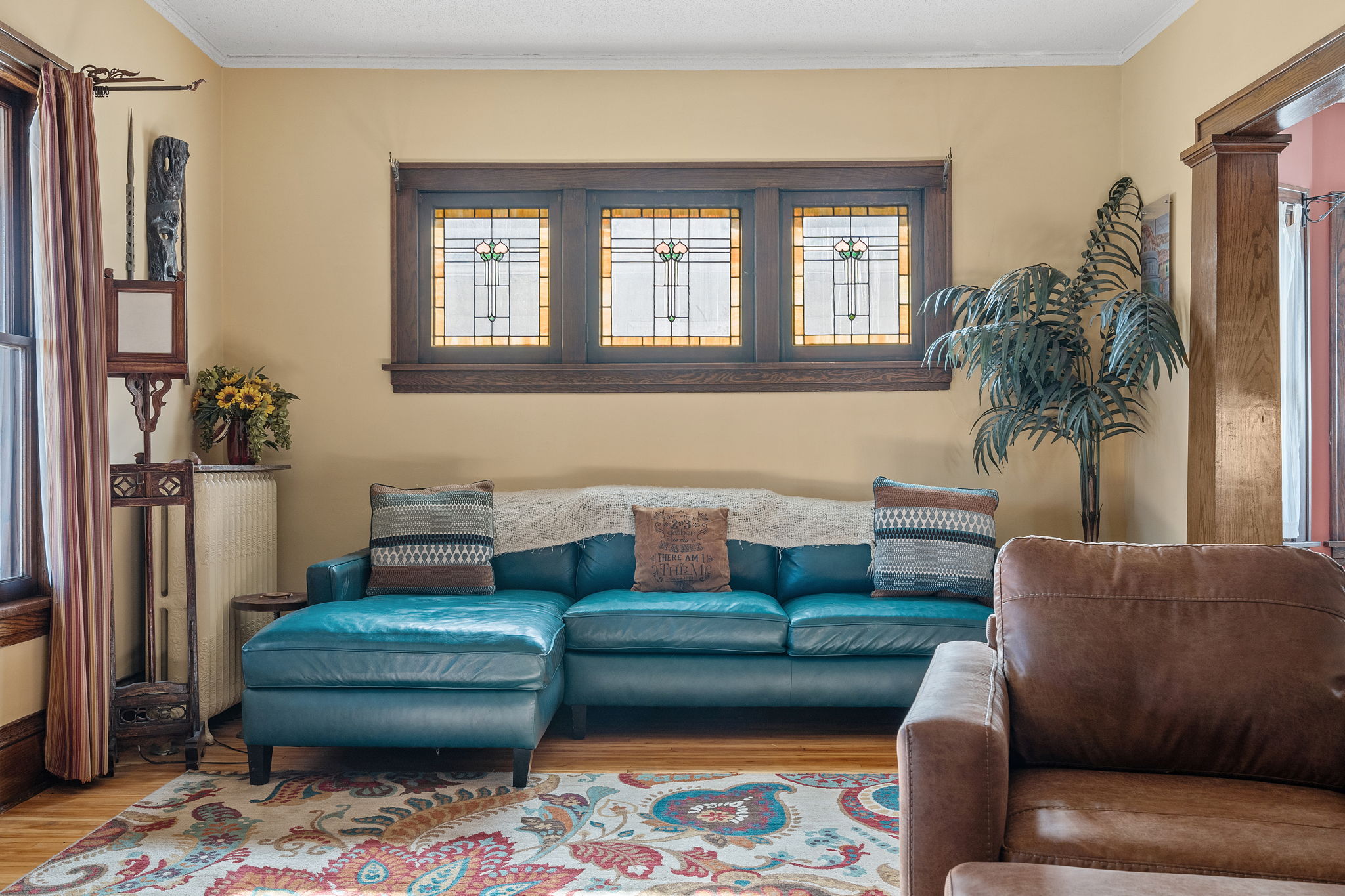 A cozy living room featuring a teal sectional couch and stunning stained-glass windows.