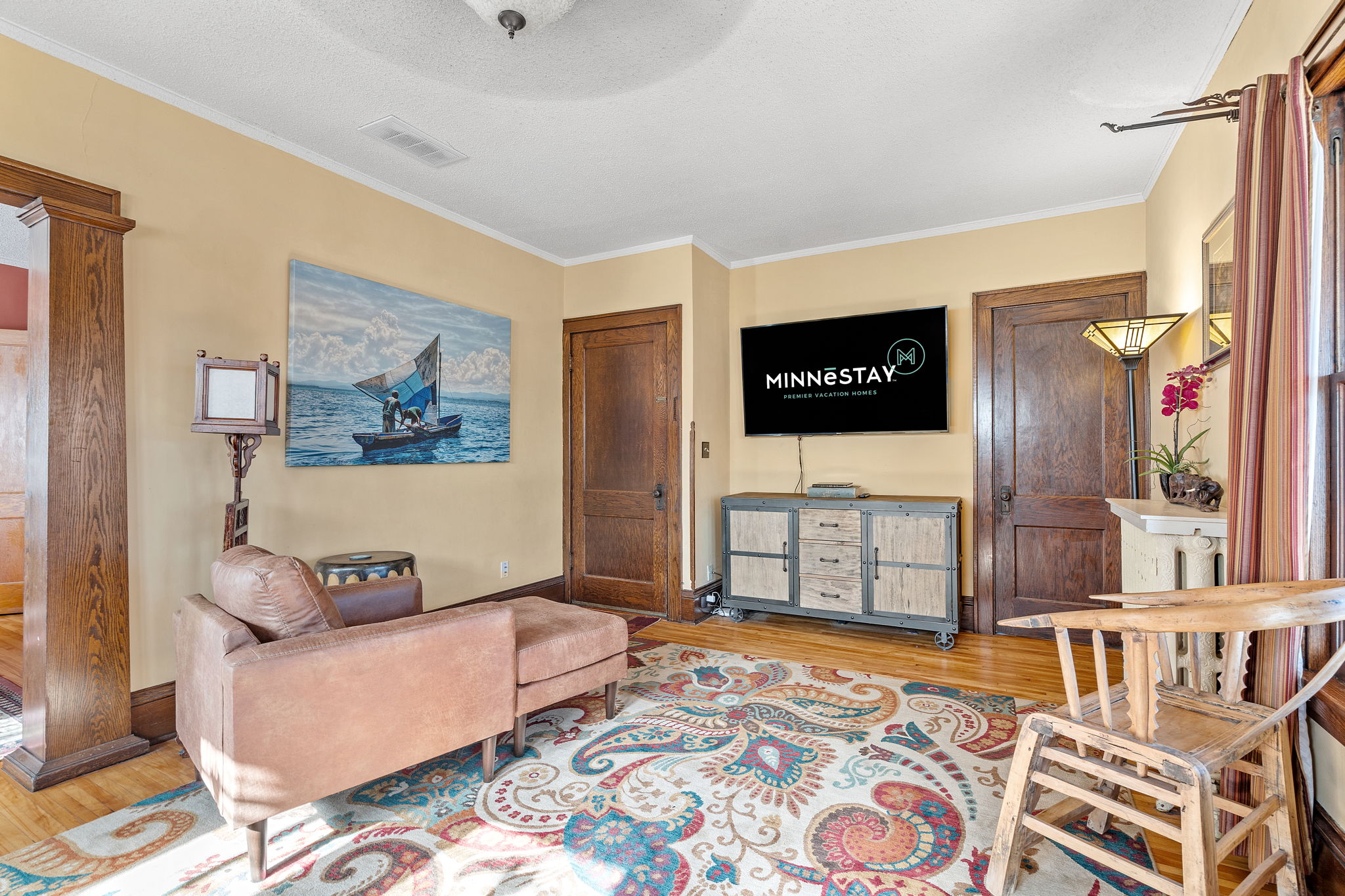 A cozy living room featuring a nautical painting, modern furniture, and homely decor.