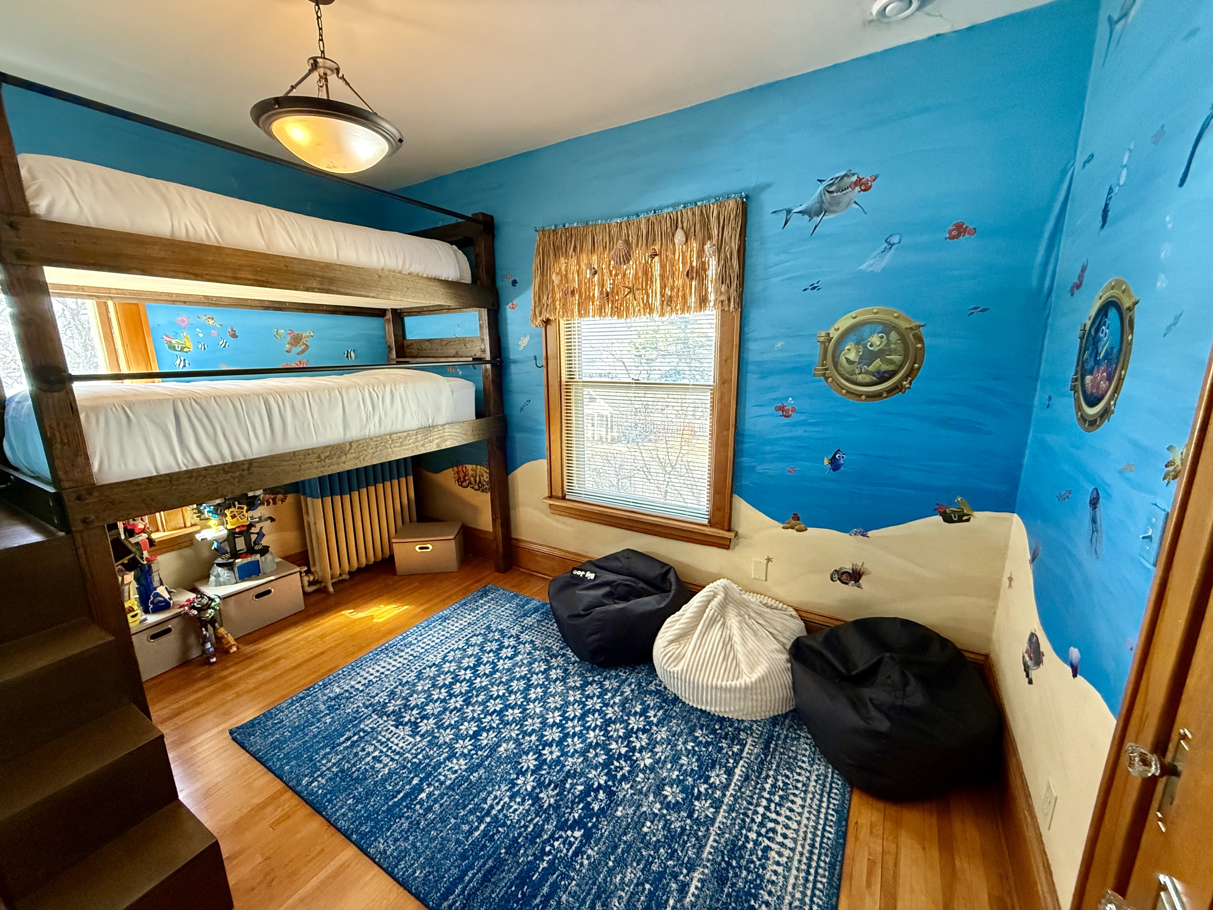 A whimsical underwater-themed children's room with a bunk bed and bright decor.