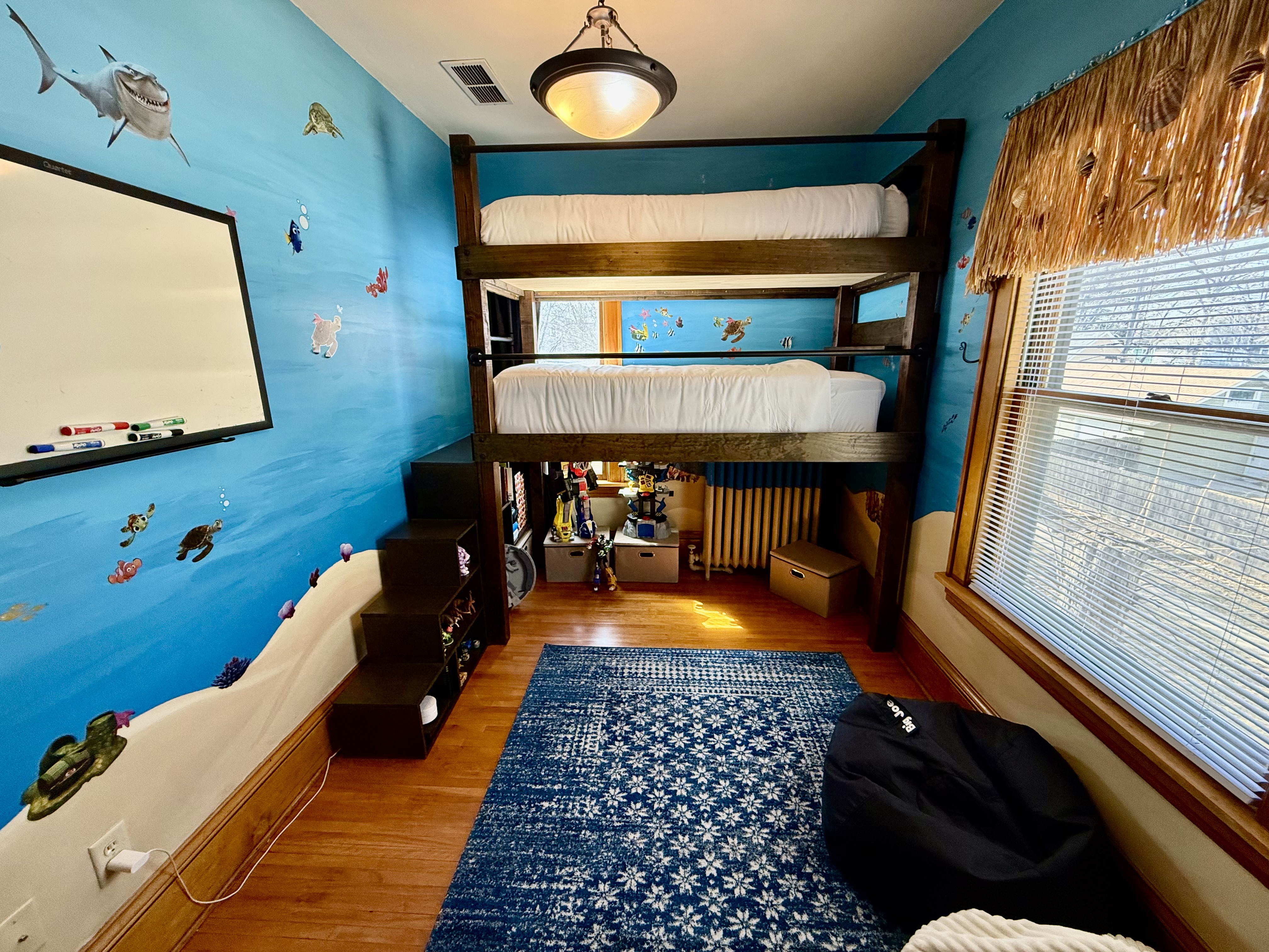 A cheerful children's bedroom with a marine-themed decor and a loft bed.