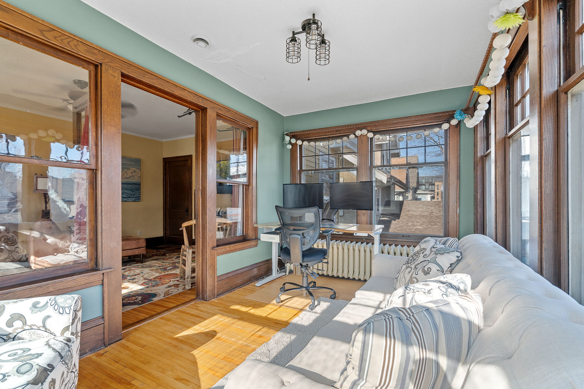 A cozy sunroom with a modern workspace, filled with natural light.