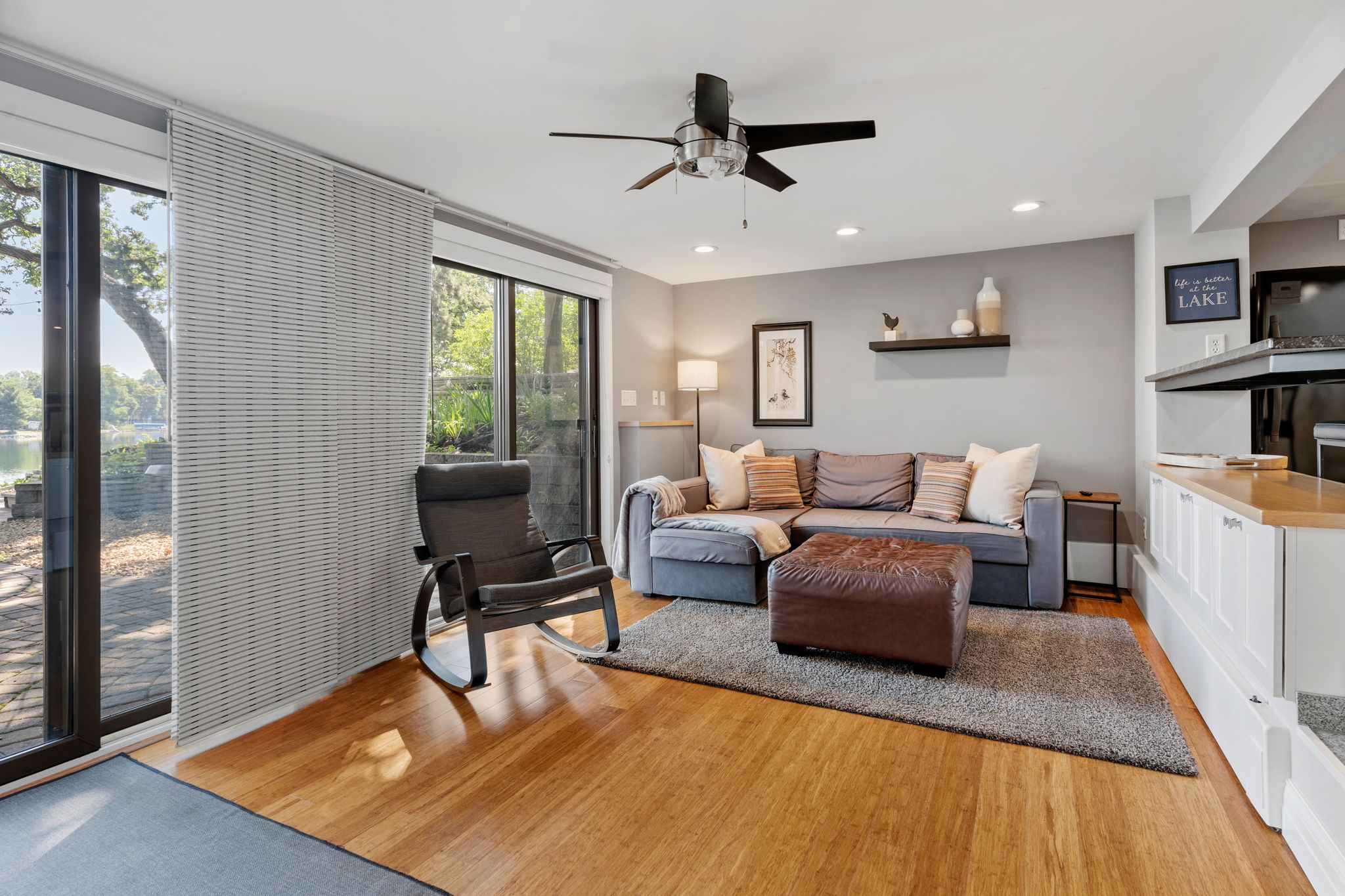 A cozy lakefront living area featuring a sectional sofa, rocking chair, and serene views.