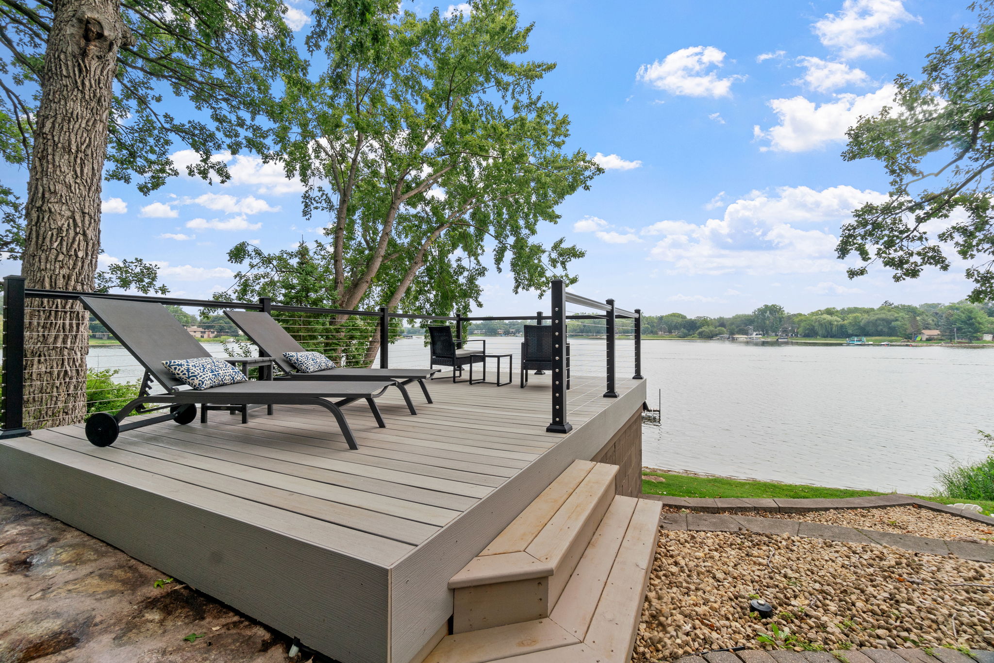 Lakeside patio with loungers and serene views.