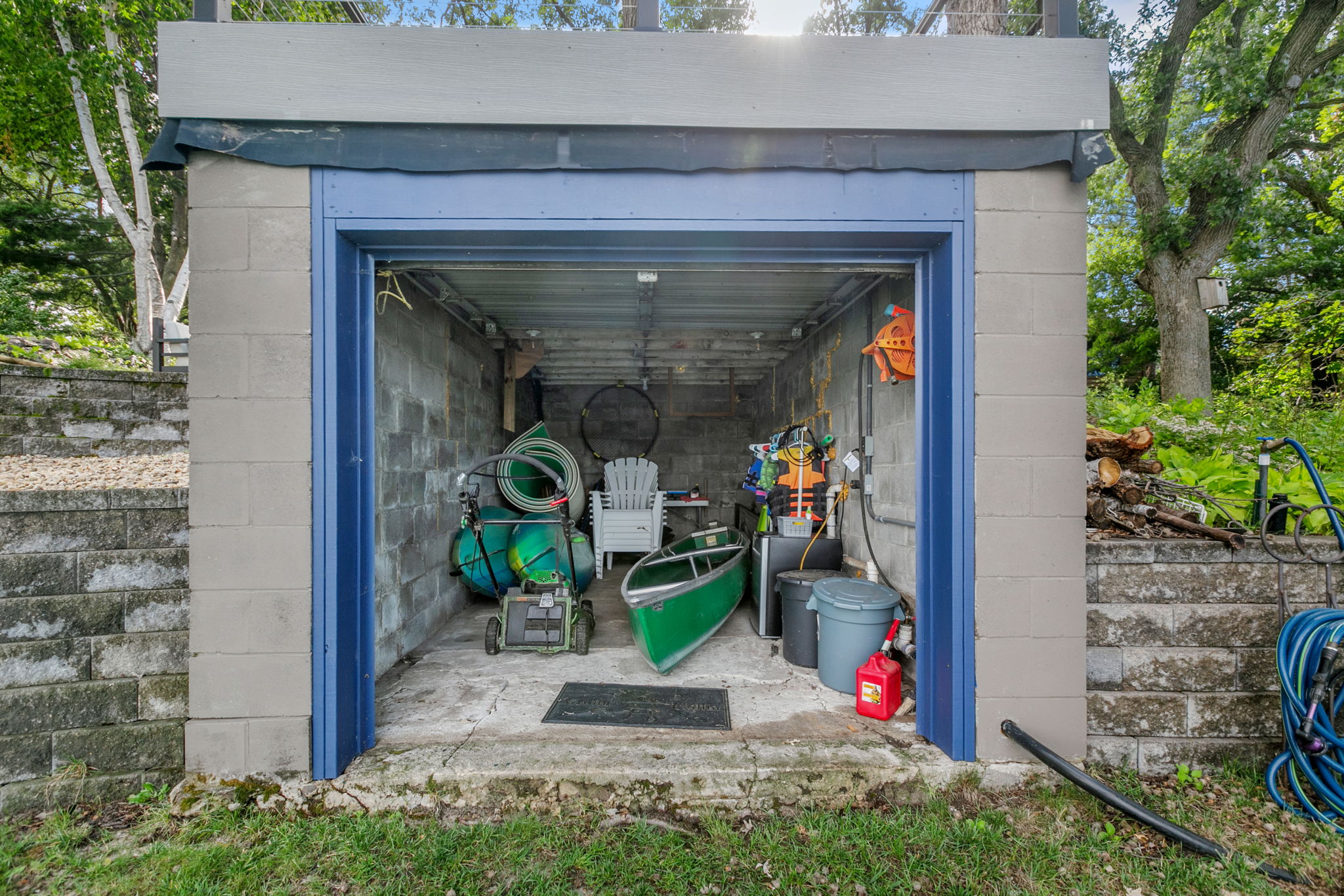 A well-organized storage shed filled with outdoor equipment and a canoe.