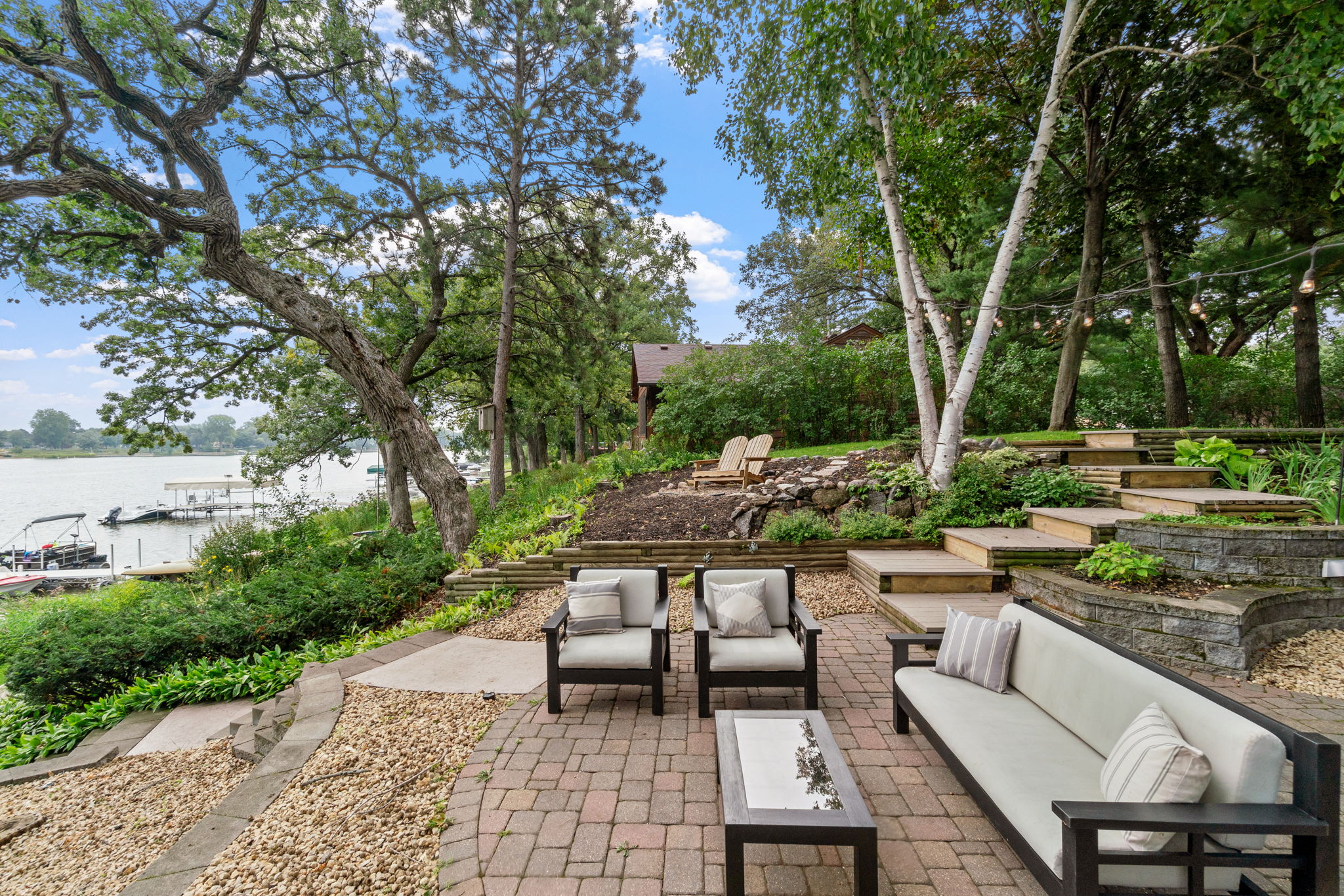 A tranquil lakeside patio with elegant seating and lush greenery.
