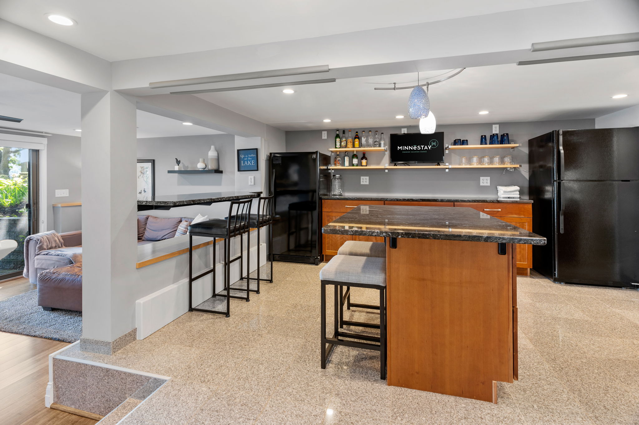 A modern kitchen and bar area featuring a sleek granite island and inviting living space.