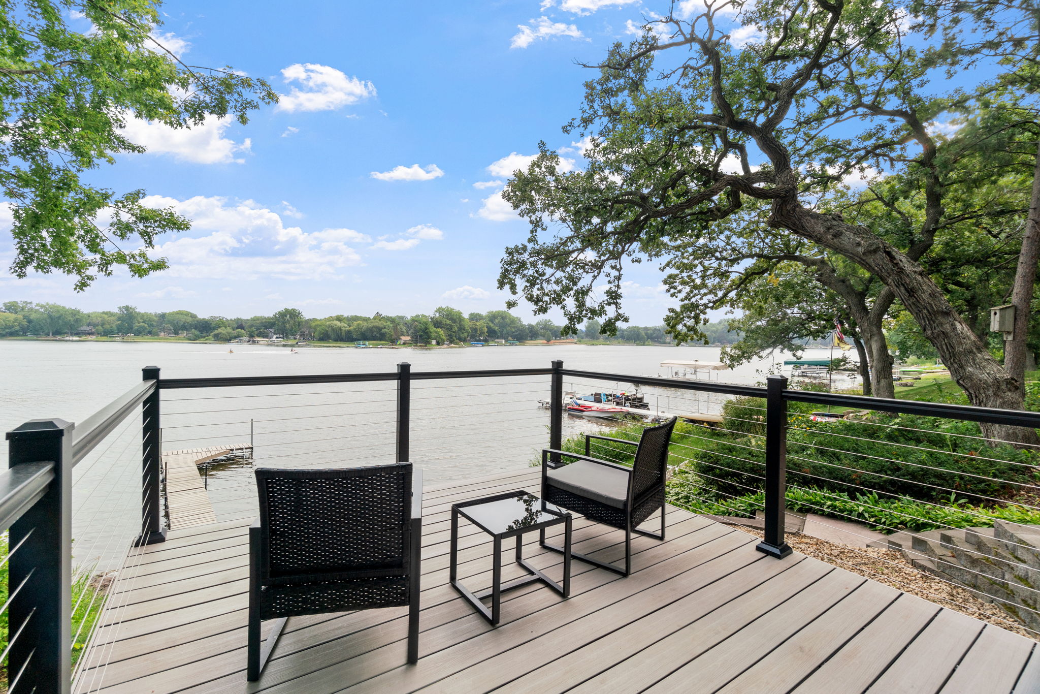 A serene deck with modern seating overlooking a lakeside view.