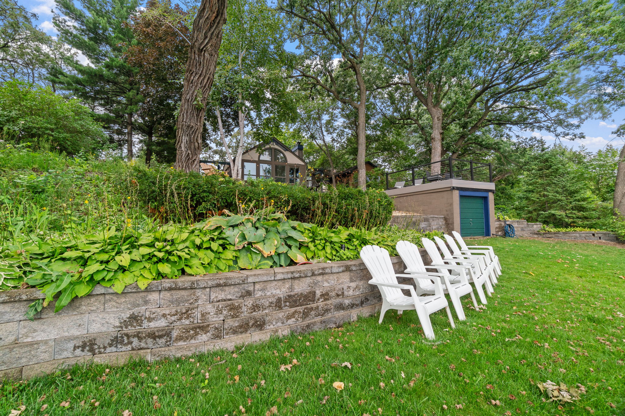A serene outdoor space with Adirondack chairs and lush landscaping.