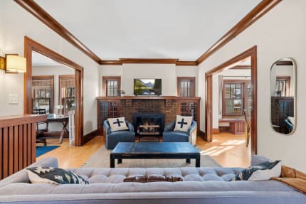 An inviting living room with a tufted sofa, blue accent chairs, and a fireplace.