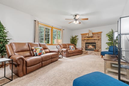 Cozy living room featuring brown reclining sofas, a brick fireplace, and blue accent chair.