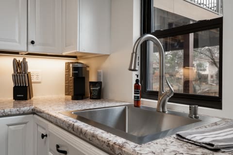 A view of a kitchen countertop with a stainless steel sink, faucet, and coffee maker.