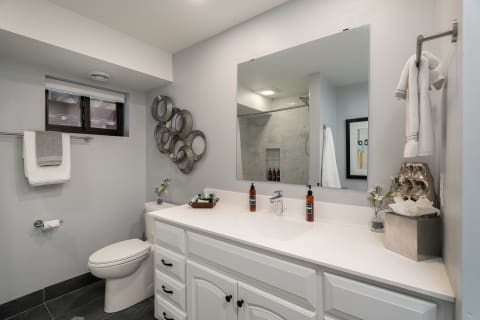 Contemporary bathroom with white vanity, circular mirrors, and neatly arranged toiletries.