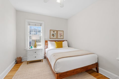 A bedroom featuring a double bed, nightstand, lamp, and decorative elements.