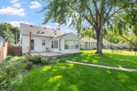 Backyard of a single-story home with a porch and lush garden.