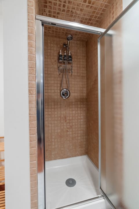 A spacious and modern shower stall featuring tiled walls and chrome fixtures.