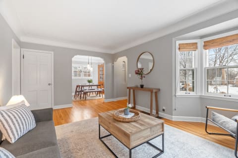 Cozy living room with gray walls, bay windows, and stylish furniture.