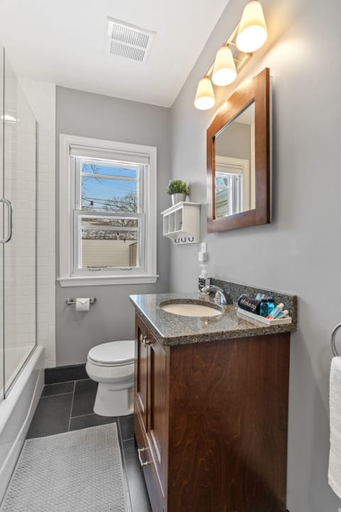 Modern bathroom with a gray color scheme, glass shower, and dark wood vanity.