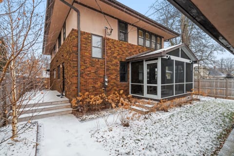 Two-story house with brick exterior and a screened porch in a winter setting.