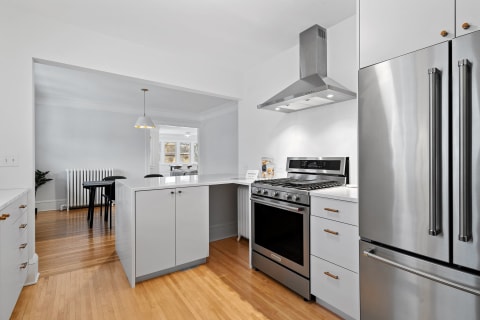 Modern kitchen featuring a white island, stainless steel oven, and dining area in the background.