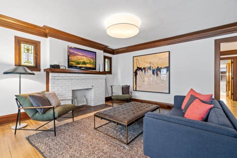 Modern living room with blue sofa, tufted coffee table, and stained glass window.
