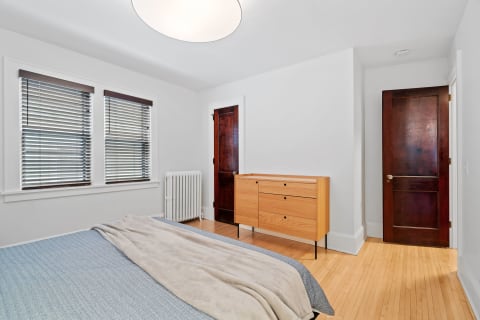 A contemporary minimalist bedroom with wooden furniture and light walls.