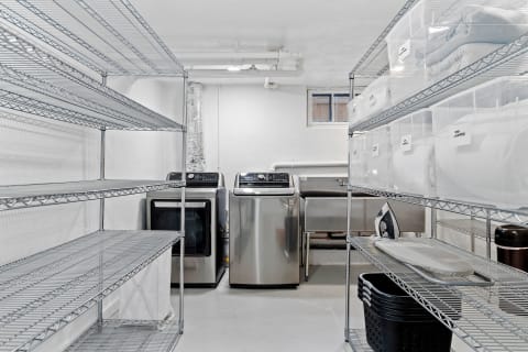 A clean laundry room with shelves, washing machines, and storage containers.