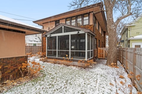 Backyard of a home with a screened porch and snow covering the ground.