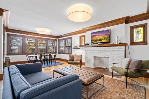 Comfortable living room with a sectional couch, a brick fireplace, and a dining area with natural light.