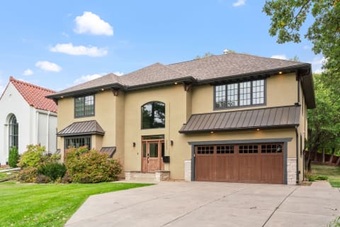 Stylish beige two-story house featuring a prominent front entrance and a two-car garage.