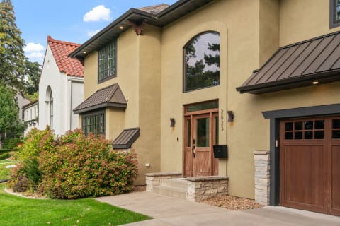 Front exterior of a modern home featuring wooden door, large windows, and vibrant shrubs.
