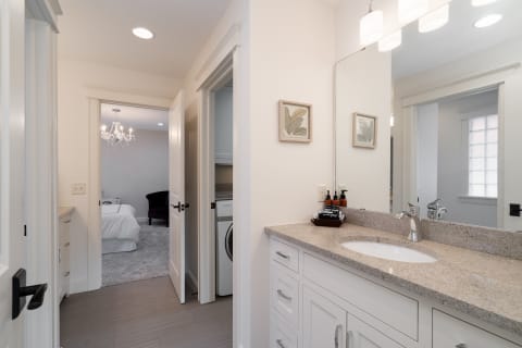 Modern bathroom view with granite countertop and adjacent bedroom.