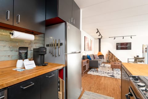 Contemporary kitchen with a view of the living space featuring a coffee maker and cozy seating.