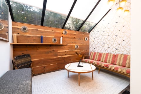 A cozy sitting area featuring a wooden wall, striped sofa, and geometric patterned feature wall.