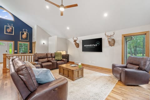 A cozy living room featuring a leather couch, mounted deer heads, and a flat-screen TV.