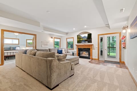 Spacious living room featuring a sectional sofa, fireplace, and mounted TV with a nature scene.