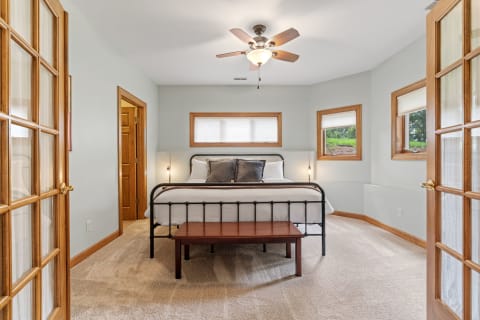 A cozy bedroom with a metal bed frame, beige carpet, and light gray walls.