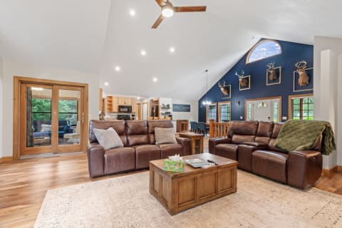 A spacious living room featuring brown leather sofas, a wooden coffee table, and deer mounts on the wall.