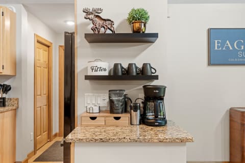 Cozy kitchen countertop with coffee maker, mugs, and decorative pieces.