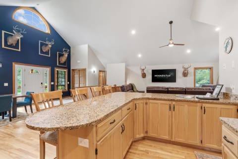 A spacious kitchen area featuring wooden cabinetry, a granite island, and deer mounts on the wall.