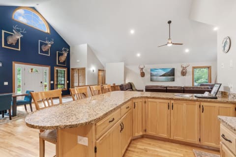 Open living area with a kitchen island, deer mounts, and leather couches.