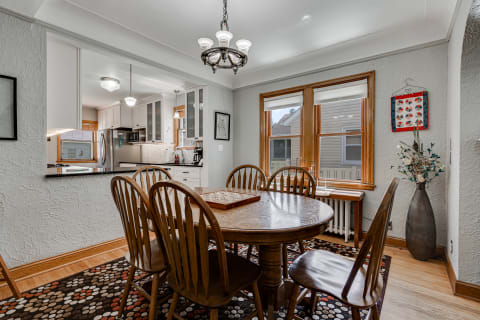 Cozy dining room with wooden table, chairs, and modern kitchen in the background.