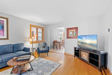 A stylish and cozy living room with a blue sofa and armchair, wooden coffee table, and a large television.