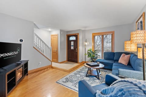 Cozy living room featuring a blue sectional sofa, coffee table, and a TV displaying a vacation home rental logo.