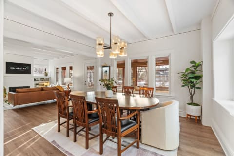 A bright dining space featuring a wooden table surrounded by chairs, with elegant pendant lighting above.