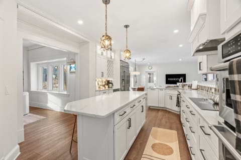 An elegant gourmet kitchen with marble countertops, premium appliances, and warm pendant lighting.
