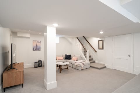 Cozy basement living space featuring a sectional sofa, coffee table, and a television.