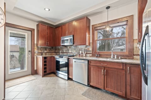 Modern kitchen featuring wooden cabinets, granite countertops, and stainless steel appliances.