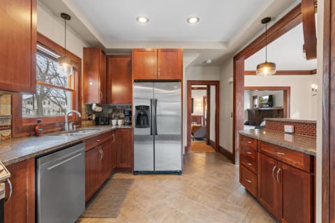 Modern kitchen with wooden cabinets and stainless steel fridge.